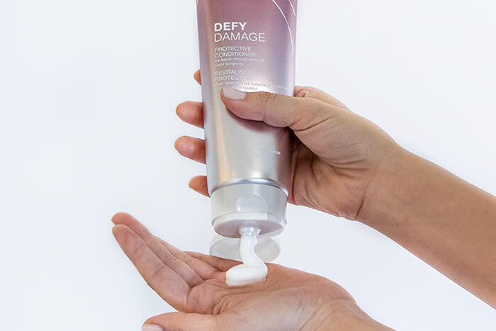 Defy damage conditioner showing product in hand