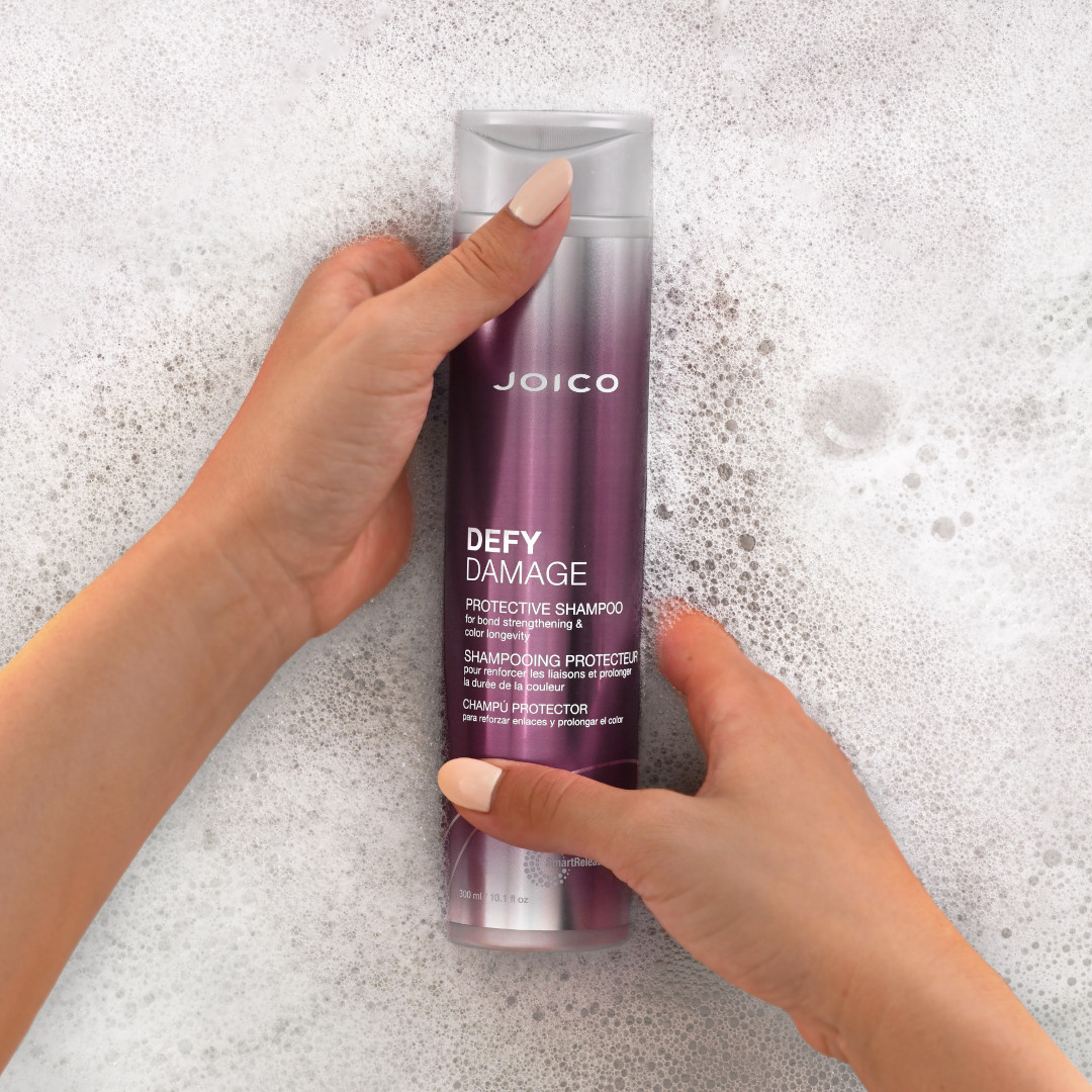 defy damage shampoo in suds with hands holding