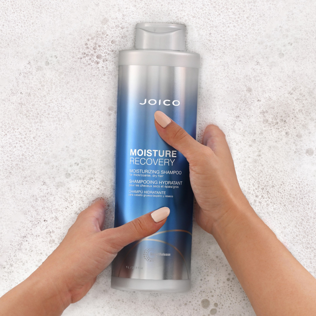 moisture recovery shampoo bottle in suds with hands holding